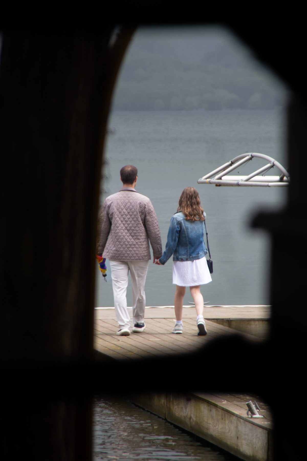 Sam and Caroline walking a dock during their engagement session